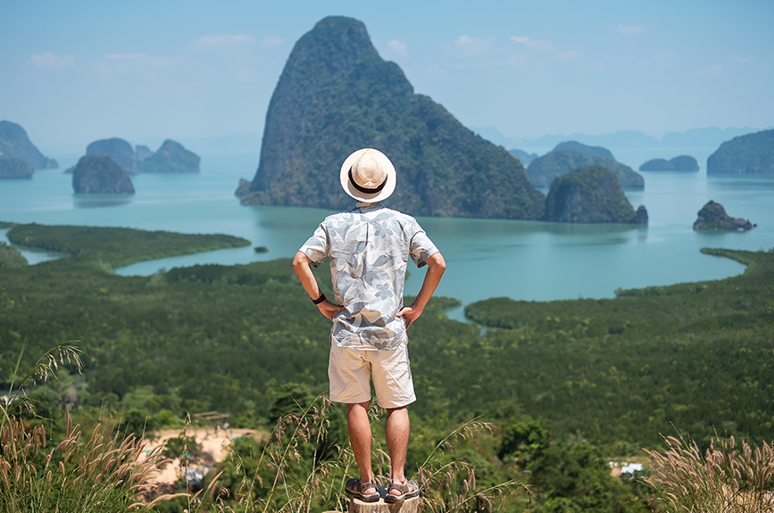 A solo traveler leisurely standing on a scenic viewpoint, overlooking huge rock formations and blue waters, similar to the islands in the Philippines.
