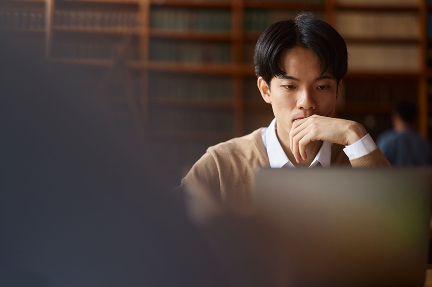 A thoughtful business professional analyzing data and context while reviewing reports on a laptop, representing the importance of reading between the lines in data and analysis for decision-making.